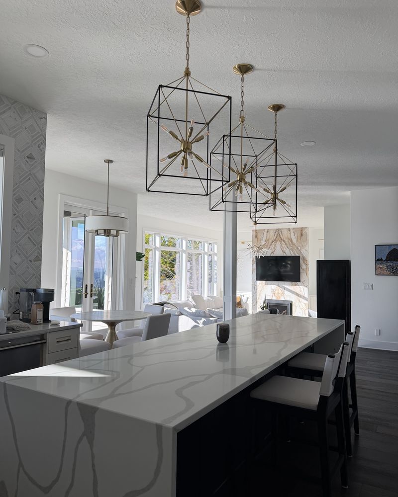 Spotless kitchen with a white marble island and gold pendant lights